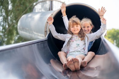 Rutschen Zwei Mädchen kommen aus einem Rutschtunnel gerutscht