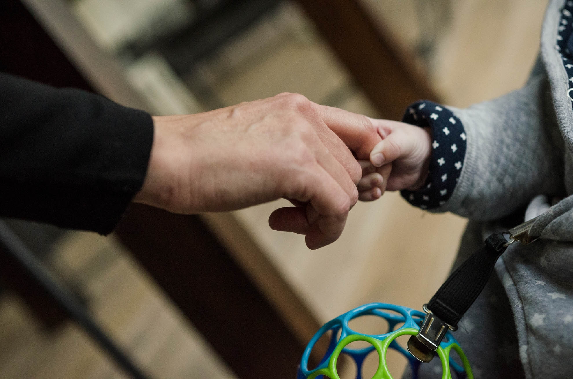 Ein Baby umfasst den Finger eines Erwachsenen