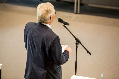 KT-Sitzung Rückenansicht eines Mannes am Mikrofon