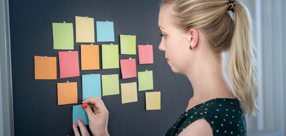 Junge Frau mit Zetteln an einer Pinwand