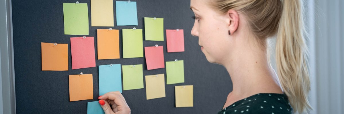 Junge Frau mit Zetteln an einer Pinwand