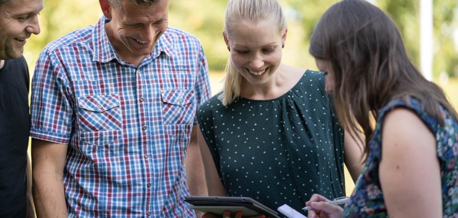Vier Personen schauen auf ein iPad