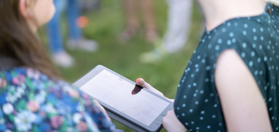 Zwei junge Frauen lachend mit Tablet in der Hand der einen Frau