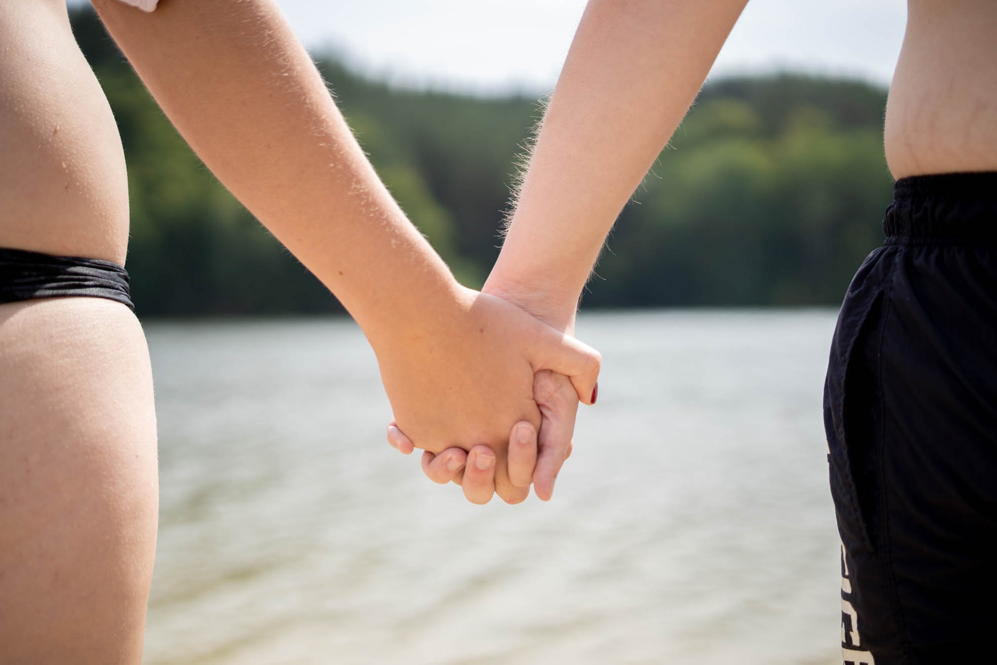 Strandbad Twistesee Junge Frau und junger Mann halten Händchen vor See