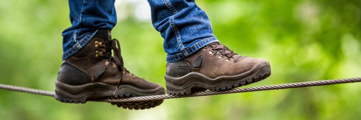 Mensch in Wanderschuhen balanciert über ein Seil