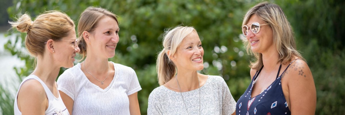 Vier junge Frauen in Sommerkleidern stehen beisammen