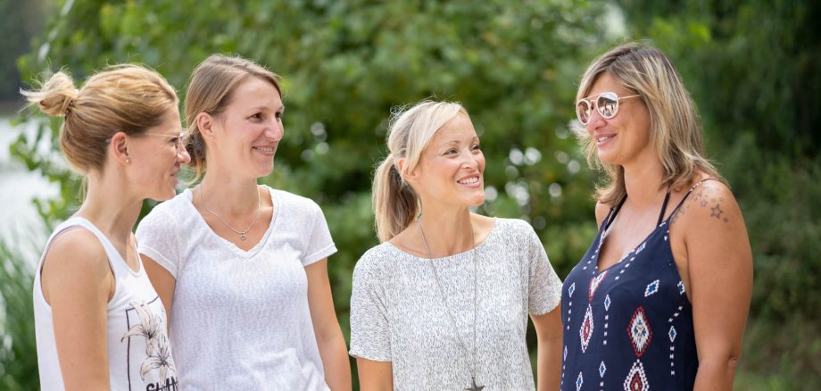 Vier junge Frauen in Sommerkleidern stehen beisammen