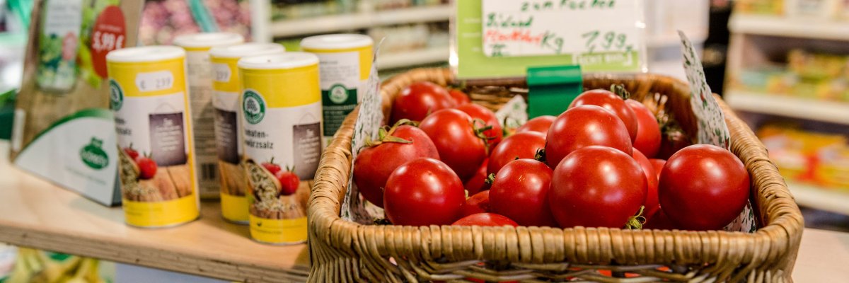 Tomaten in Weidenkorb und Gewürzstreuer stehen auf einem Tisch