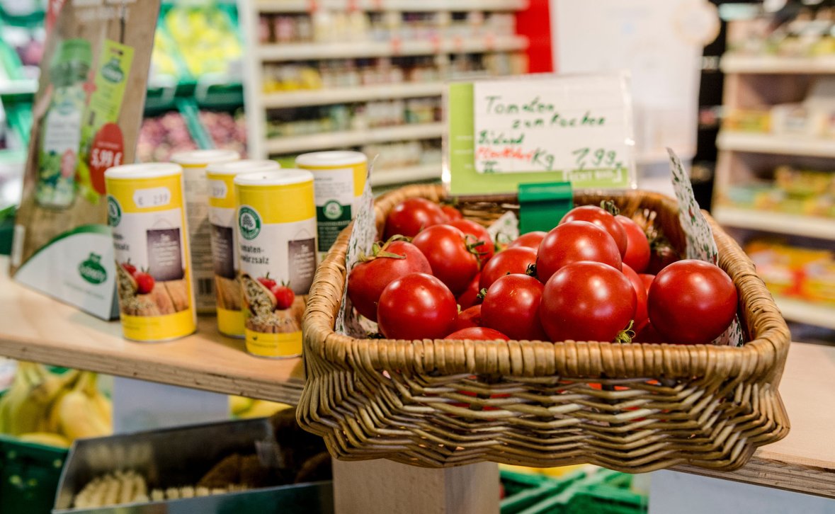Tomaten in Weidenkorb und Gewürzstreuer stehen auf einem Tisch