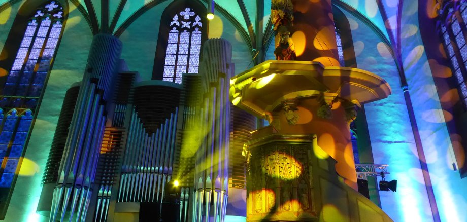 Grün, blau und gelb beleuchtete Orgel in einer gotischen Hallenkirche