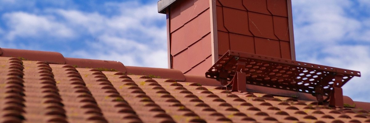 Schornstein auf einem Dachfirst vor blauem Himmel