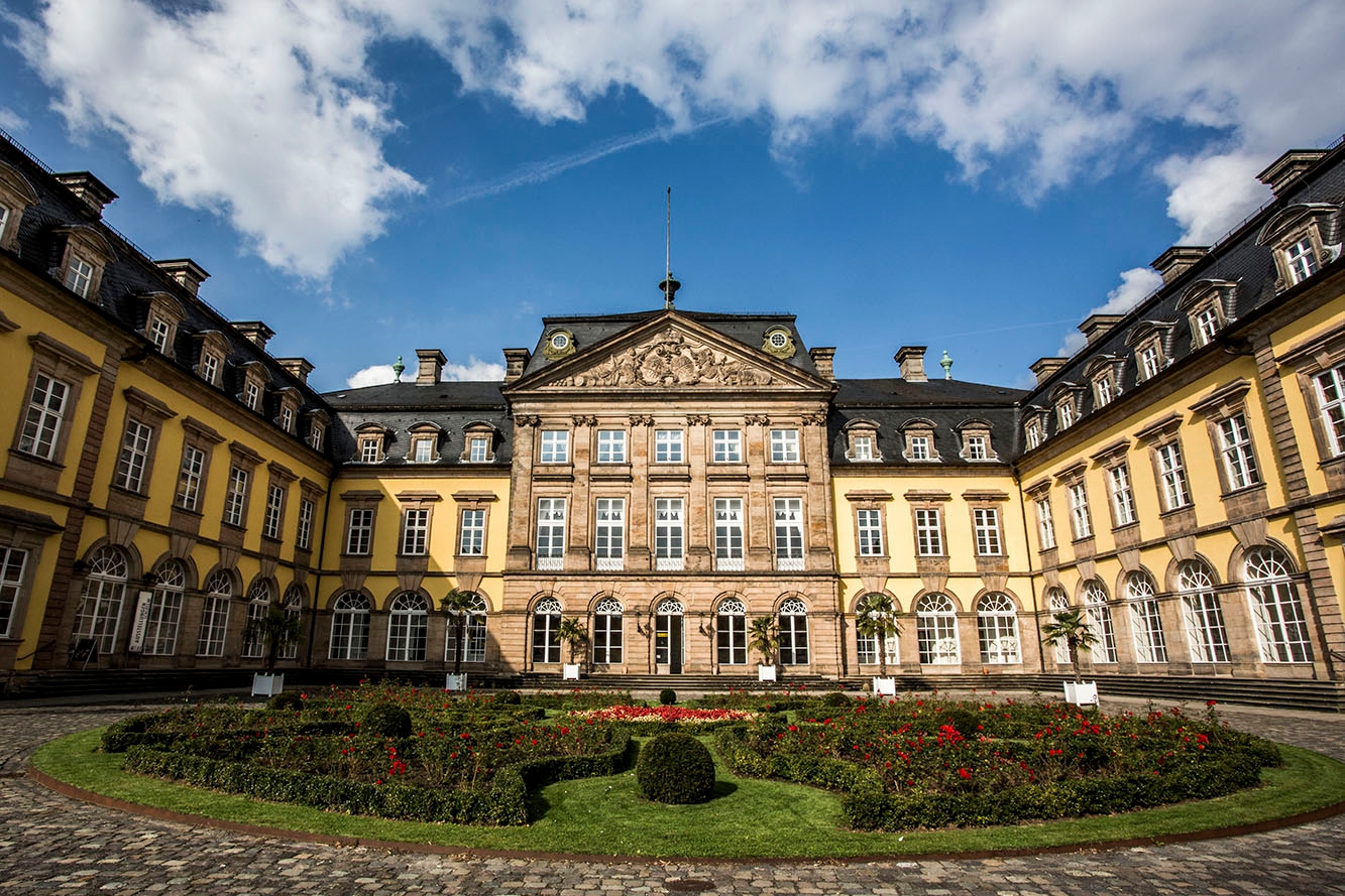 Schloss Bad Arolsen mehrstöckiges Schlossgebäude mit gelben Steinen und grauem Dach und Blumenrabatte im Innenhof